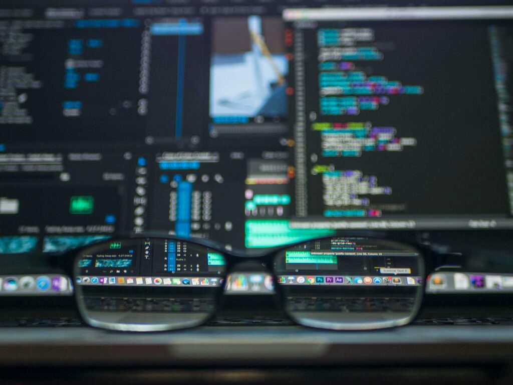 Veille & Entreprise Eyeglasses reflecting computer code on a monitor, ideal for technology and programming themes.